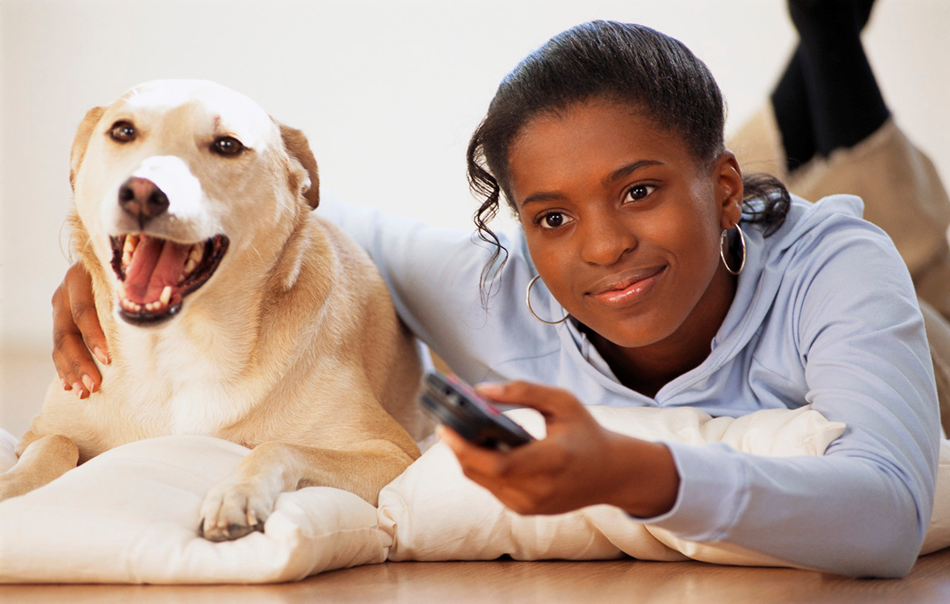 Flea and Tick Prevention. Picture of a young black girl laying on the floor with her dog.